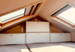Cozy loft sleeping area with skylights and built-in storage at Beach sleep house Dishoek 37, Netherlands.