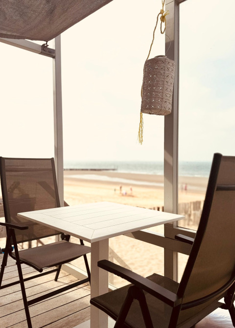 Deux chaises et une table sur une terrasse avec vue sur la plage au Beach Sleep House Dishoek 37, à Zeeland.