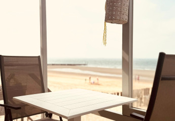 Deux chaises et une table sur une terrasse avec vue sur la plage au Beach Sleep House Dishoek 37, à Zeeland.