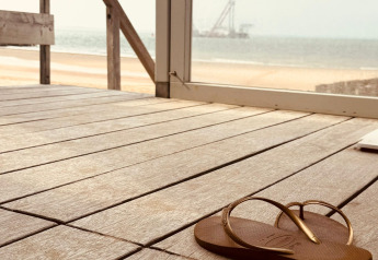 Une tong marron sur une terrasse en bois avec vue sur la plage et la mer à Dishoek, Zeeland, Pays-Bas.
