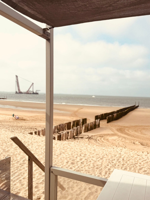View from Beach sleep house «Dishoek 37» in Dishoek, Zeeland, Netherlands, showing sandy beach and ocean.