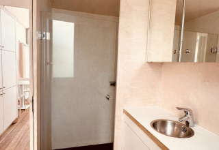 Moderne badeværelse i et tiny house med trægulv, brusekabine og vask i Beach sleep house Dishoek 37.