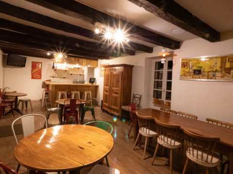 Sala da pranzo interna al campeggio Le Moulin de Bel Air in Occitania, Francia, con arredi in legno e bar.