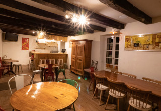 Sala da pranzo interna al campeggio Le Moulin de Bel Air in Occitania, Francia, con arredi in legno e bar.