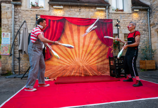 Due clown fanno giochi di prestigio con clave davanti a un tendone circense in un campeggio in Occitania.