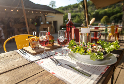 Cena all'aperto con insalata, patatine, hamburger e vino rosato al Le Moulin de Bel Air in Occitania, Francia.