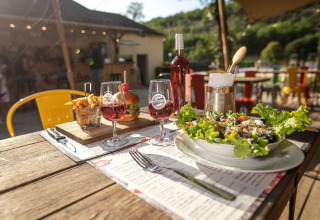 Cena all'aperto con insalata, patatine, hamburger e vino rosato al Le Moulin de Bel Air in Occitania, Francia.
