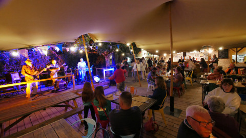 Scena serale all'aperto con musica dal vivo e ospiti al campeggio Le Moulin de Bel Air in Occitania, Francia.