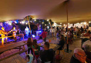 Scena serale all'aperto con musica dal vivo e ospiti al campeggio Le Moulin de Bel Air in Occitania, Francia.
