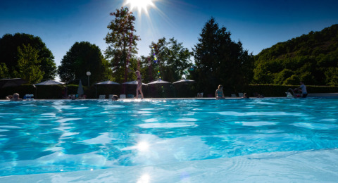Giornata di sole in piscina al campeggio Le Moulin de Bel Air in Occitania, Francia, con ospiti rilassati.