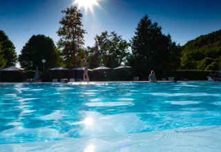 Giornata di sole in piscina al campeggio Le Moulin de Bel Air in Occitania, Francia, con ospiti rilassati.