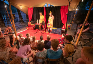 Children watch a magician performing on an outdoor stage at Le Moulin de Bel Air campsite, Occitanie, France.