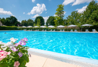 Piscina al aire libre en el camping Le Moulin de Bel Air en Occitania, Francia, rodeada de tumbonas y flores.