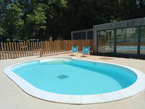 Buitenzwembad met helderblauw water, ligzetels en houten omheining op Campsite Seasonova Vittel in Grand Est, Frankrijk.