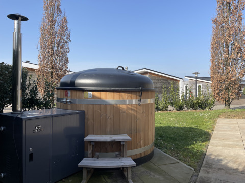 Houten hottub met kachel en trapje bij lodge Biesbosch op Resort Mooi Bemelen in Nederland.