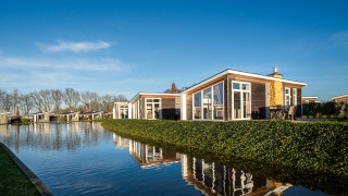 Lodge moderne à Biesbosch avec jacuzzi, grandes baies vitrées et terrasse donnant sur l’eau par beau temps.