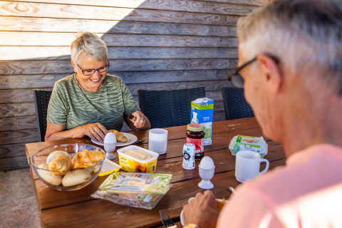 Couple senior partageant un petit déjeuner en plein air au Resort Mooi Bemelen, aux Pays-Bas, avec pain et œufs.