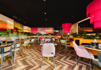 Moderne restaurantinteriør på Lodge Biesbosch, Resort Mooi Bemelen, med farverige stole og lamper.