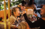 Une femme donne à manger à une fillette souriante dans un restaurant de lodge à l'ambiance chaleureuse.