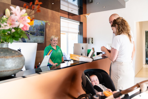 Onthaal bij Biesbosch Lodge in Resort Mooi Bemelen, Nederland, familie met baby aan de balie.