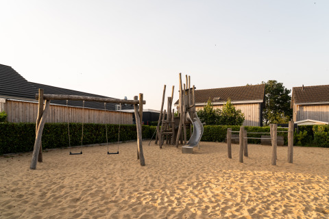 Speeltuin met schommels en glijbaan op zand bij Resort Mooi Bemelen, aan de Biesbosch-lodge.