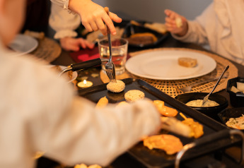 Kinderen koken en eten samen rond de tafel in lodge Biebosch, Resort Mooi Bemelen, Nederland.