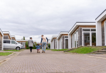 Famille marchant entre des lodges modernes au Resort Mooi Bemelen, lodge Biebosch, aux Pays-Bas.