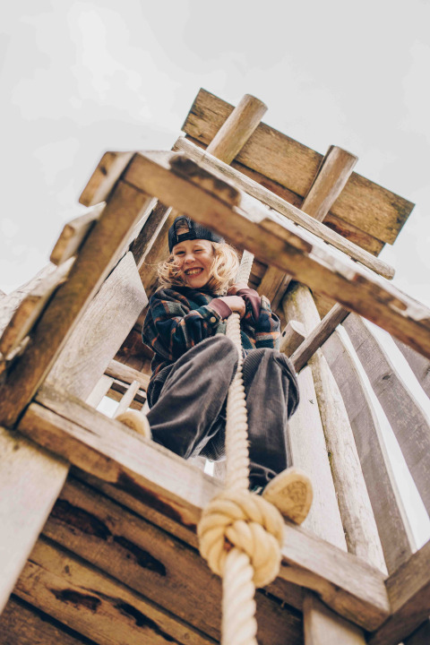Enfant jouant à une corde dans une structure en bois au lodge « Biebosch » du Resort Mooi Bemelen, Pays-Bas.