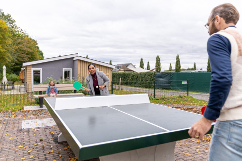 Gezin speelt buiten tafeltennis bij een lodge op Resort Mooi Bemelen in Nederland.