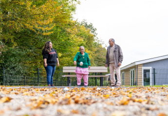 Drie personen spelen petanque op een met bladeren bezaaid terrein bij lodge Biebosch, Resort Mooi Bemelen.