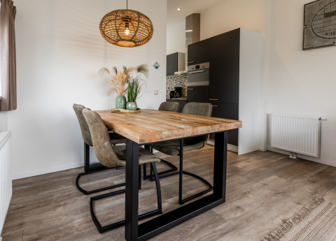 Moderne eetruimte in een lodge met houten tafel, vier stoelen, decoratieve vaas en stijlvolle lamp.