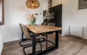 Salle à manger moderne dans un lodge avec table en bois, quatre chaises, vase décoratif et luminaire design.