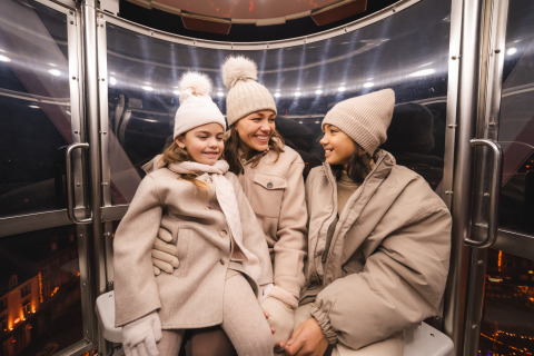 Trois personnes en manteaux d'hiver et bonnets sourient ensemble dans une gondole à Resort Mooi Bemelen, Pays-Bas.
