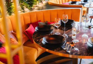 Table élégante dressée avec assiettes noires et verres à Biebosch - Sunshower, Resort Mooi Bemelen, Pays-Bas.
