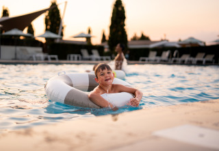 Garçon nageant avec une bouée à Biebosch - Sunshower, Resort Mooi Bemelen, Pays-Bas, au coucher du soleil.
