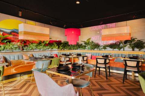 Intérieur de restaurant tendance avec sièges colorés, plantes et néon chez Biebosch - Sunshower, Resort Mooi Bemelen.