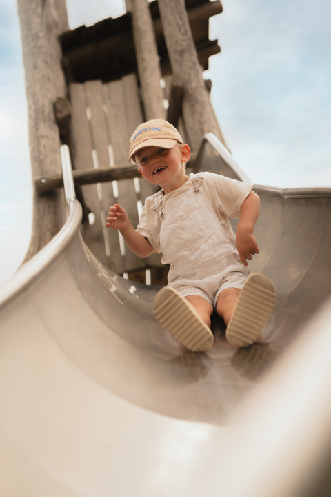 Un enfant en vêtements clairs glisse sur un toboggan à Biebosch - tuinhuis au Resort Mooi Bemelen aux Pays-Bas.
