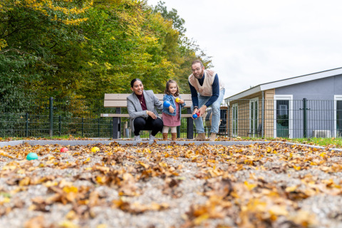 Famille jouant avec des boules en automne au Biebosch - tuinhuis, Resort Mooi Bemelen, aux Pays-Bas.