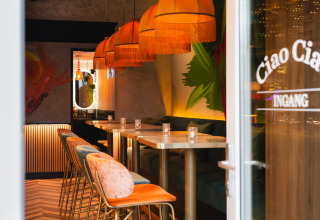 Inkijk in een trendy lodge met warme lampen, kleurrijke stoelen en gezellige, moderne inrichting.