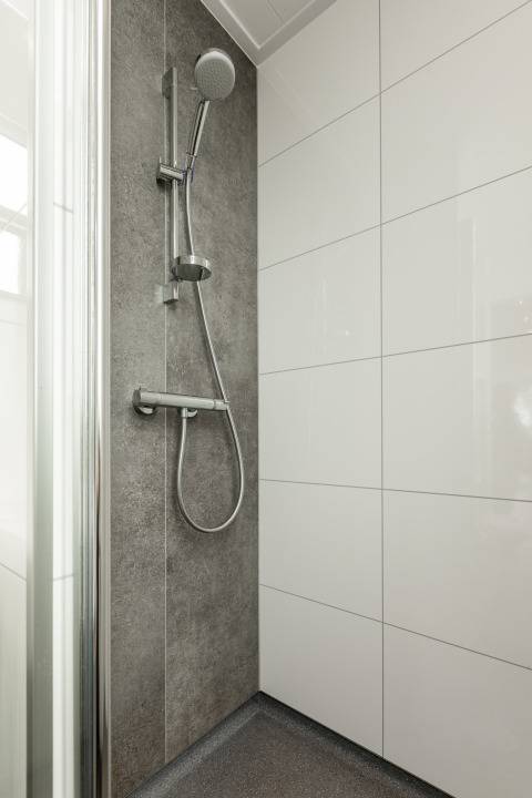 Douche moderne avec carrelage gris et pommeau à Biebosch - tuinhuis, Resort Mooi Bemelen, Pays-Bas.