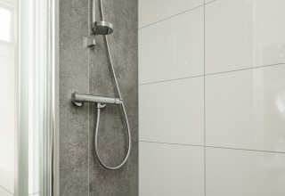 Douche moderne avec carrelage gris et pommeau à Biebosch - tuinhuis, Resort Mooi Bemelen, Pays-Bas.