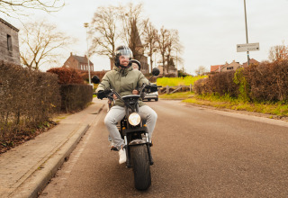 Deux personnes roulent en scooter près de Biebosch - tuinhuis au Resort Mooi Bemelen, aux Pays-Bas.