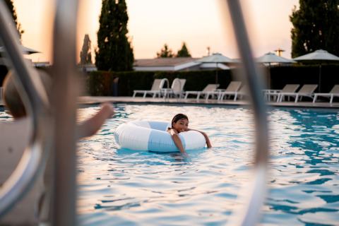 Enfant se détendant sur une bouée blanche dans une piscine extérieure au coucher du soleil au Resort Mooi Bemelen, Pays-Bas.