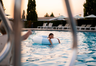Enfant se détendant sur une bouée blanche dans une piscine extérieure au coucher du soleil au Resort Mooi Bemelen, Pays-Bas.