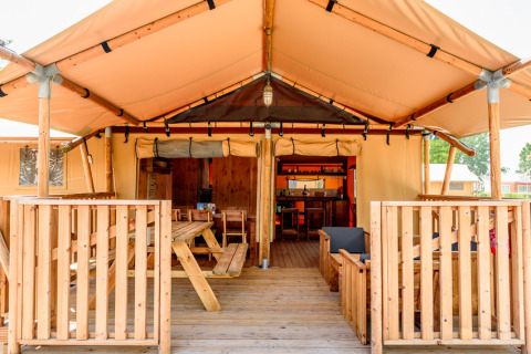 Tente safari au Dune Agriturismo en Italie avec terrasse en bois, coin repas et coin salon extérieur.