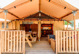 Safari-Zelt im Dune Agriturismo in Italien mit Holzterrasse, Sitz- und Essbereich im Freien.