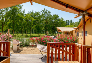 Udsigt fra en safaritelts terrasse ved Dune Agriturismo i Italien, omgivet af træer og blomster.