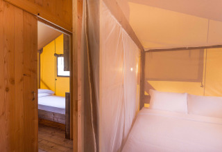 Innenaufnahme eines Safari-Zeltes im Dune Agriturismo in Italien mit Betten und Holzwänden.
