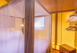 Intérieur d'une tente safari au Dune Agriturismo en Italie, avec moustiquaire et meubles en bois.