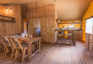 Interieur van een safaritent bij Dune Agriturismo in Italië met houten meubelen en gezellige keukenhoek.